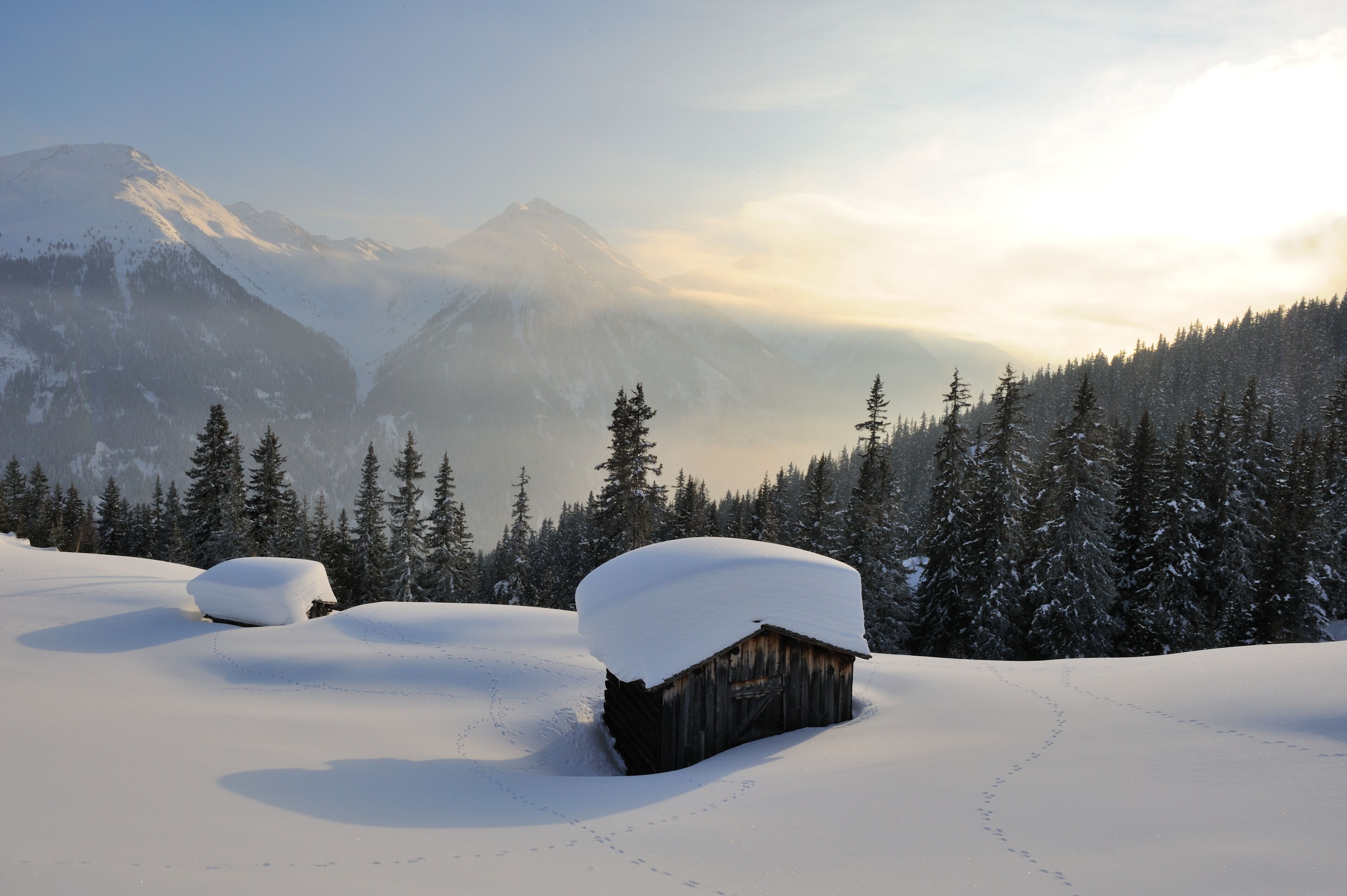 Hütte in winterlicher Landschaft ist mit Meterhohem Schnee bedeckt.