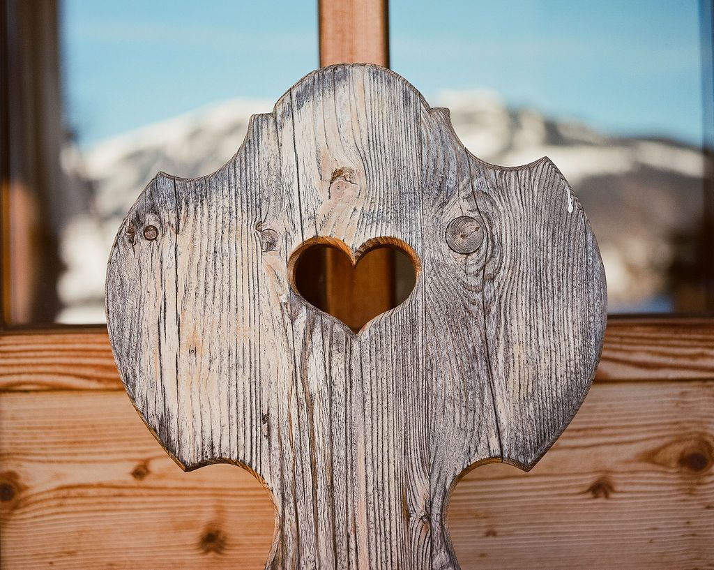 Traditioneller Holzstuhl mit einem geschnitzten Herzausschnitt und Blick auf die Berglandschaft